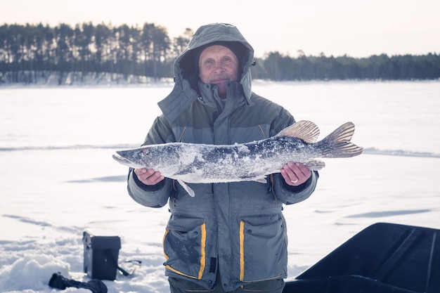 Un hombre sostiene pesca en hielo de invierno de lucio grande