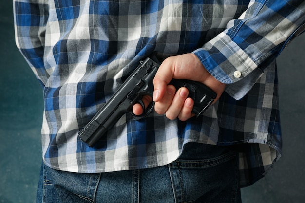 Foto un hombre sostiene una pistola por detrás. arma de autodefensa