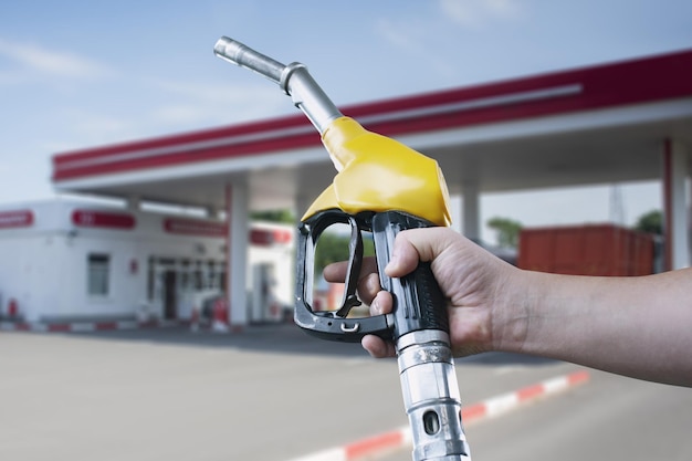 El hombre sostiene una pistola de reabastecimiento de combustible en la mano para reabastecer automóviles Estación de servicio con combustible diesel y gasolina cerrado