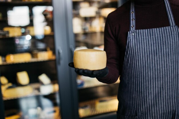 Un hombre sostiene queso en las manos en la fábrica de queso