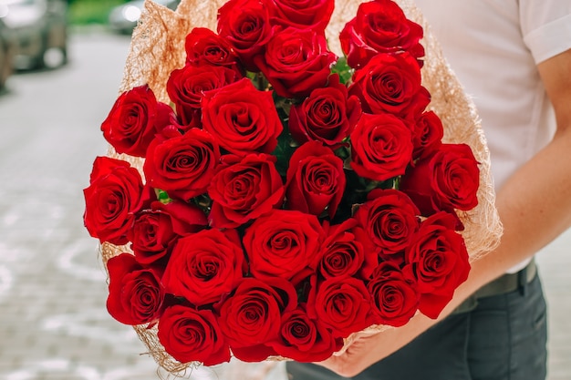 El hombre sostiene un ramo de rosas rojas para su amada