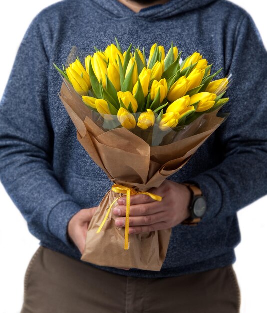 El hombre sostiene un ramo de tulipanes amarillos relacionados con la cinta del Día de San Valentín