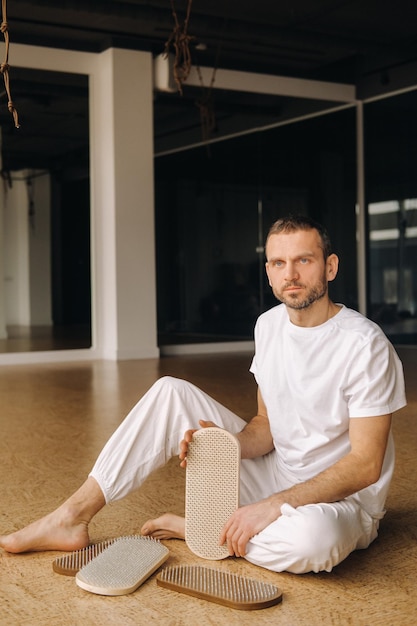 Un hombre sostiene en sus manos tablas con clavos para clases de yoga.