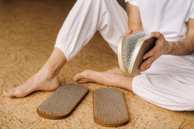 Un hombre sostiene en sus manos tablas con clavos para clases de yoga.