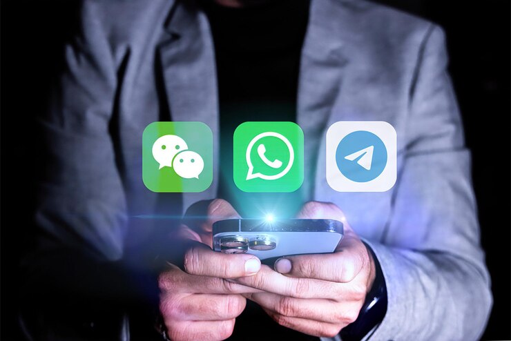 Un hombre sostiene un teléfono celular con un icono verde que dice mensajero en él