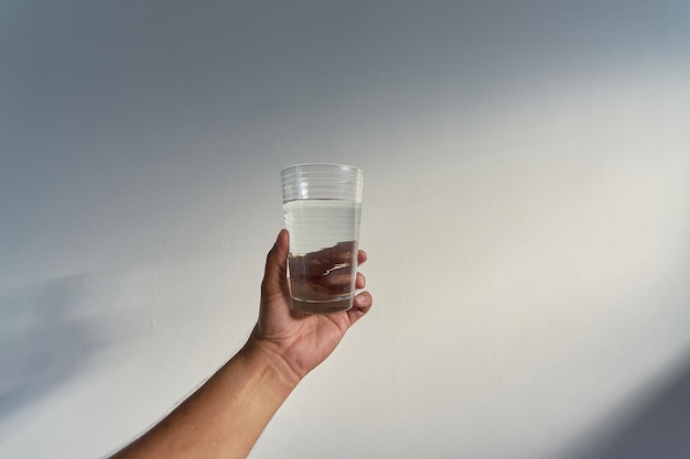 Un hombre sostiene un vaso de agua en la mano.