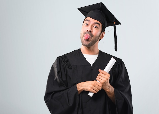 Hombre en su día de graduación Universidad hace emoción de cara divertida y loca sobre fondo gris