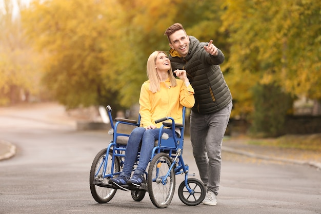 Hombre con su esposa en silla de ruedas al aire libre en día de otoño