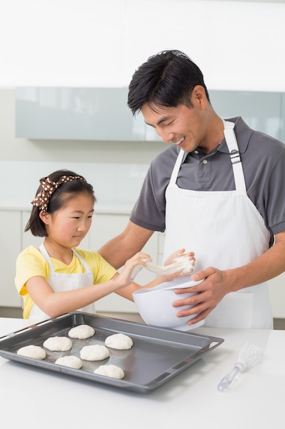 Hombre con su hija preparando galletas en la cocina