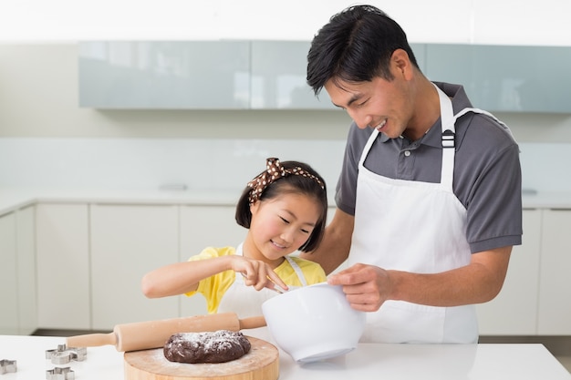 Hombre con su hija preparando masa en la cocina