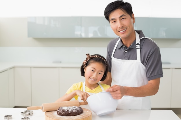 Hombre con su hija preparando masa en la cocina