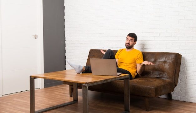 Hombre con su laptop en una habitación infeliz y frustrada con algo porque no entiende algo.