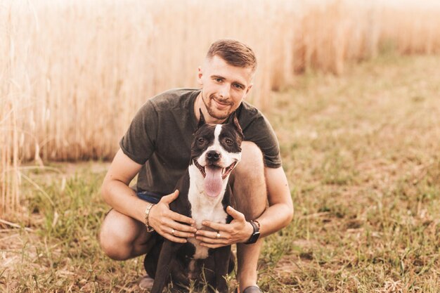 Hombre con su perro abrazando y jugando al aire libre en el parque