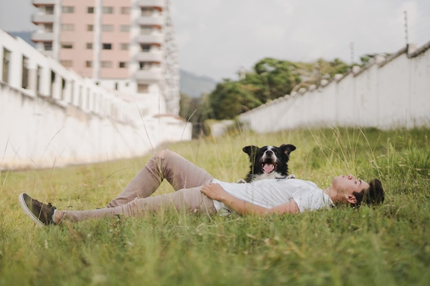 Un hombre y su perro tirados en la hierba.