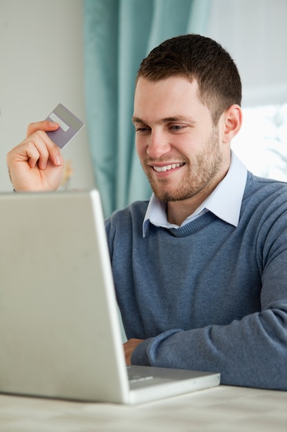 Foto hombre con su tarjeta de crédito en su computadora portátil