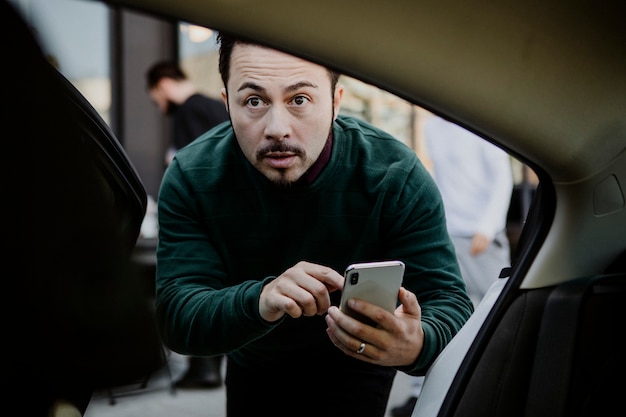 Hombre con su teléfono móvil entrando en un coche