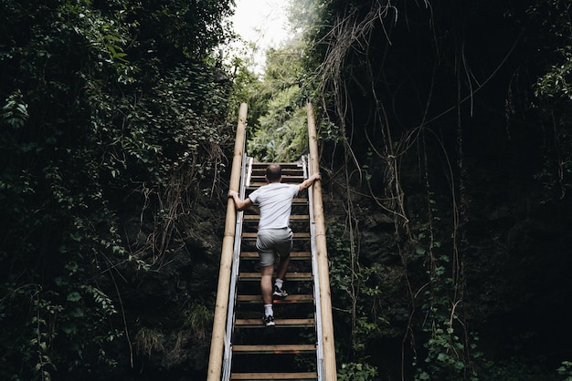 El hombre sube un empinado tramo de escaleras rodeado de vegetación