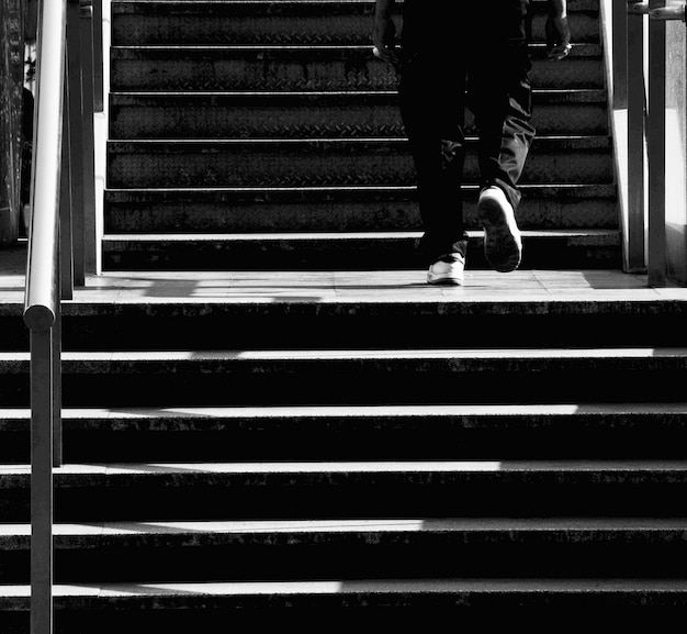 Hombre se sube en una escalera de hormigón en la ciudad - monocromo