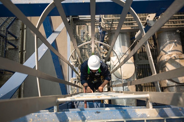 El hombre sube el tanque de inspección visual de almacenamiento de escaleras