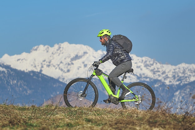 Hombre subiendo un prado de montaña con bicicleta de montaña