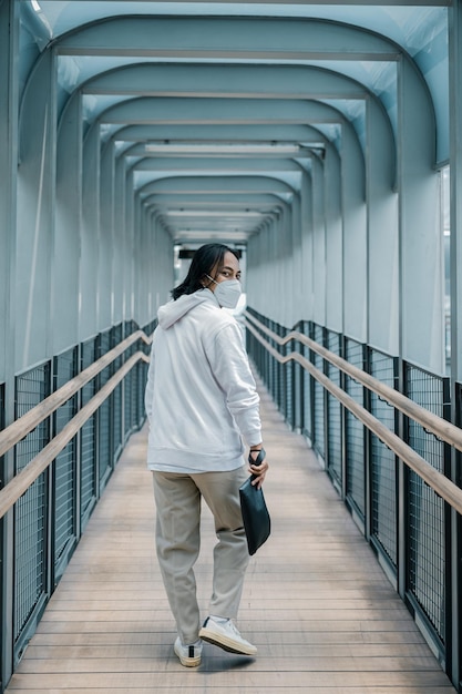 Foto hombre con sudadera con capucha caminando sobre un puente peatonal