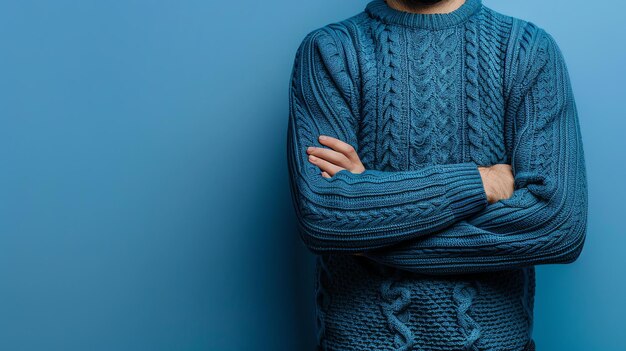 Foto un hombre con un suéter azul con una expresión seria en su cara está de pie con los brazos cruzados