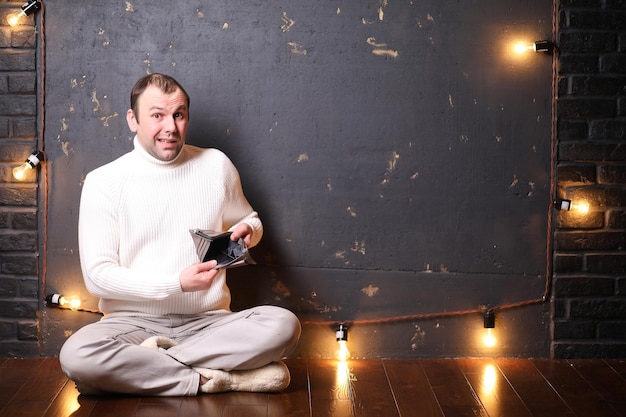 Un hombre con un suéter blanco en una habitación oscura escuchando música.