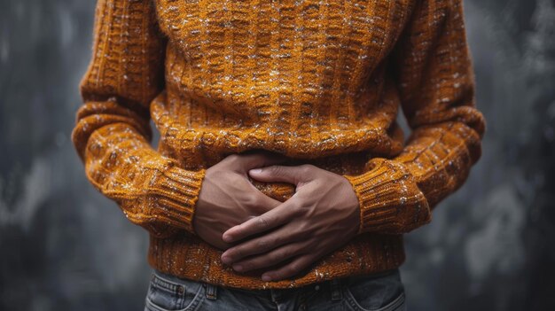 Foto hombre con suéter naranja sosteniendo el estómago en un fondo gris imagen conceptual de salud