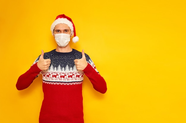 Hombre de suéter de Navidad con renos da Thumbs up aislado fondo amarillo con espacio para tex