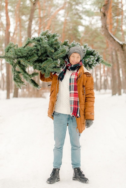 Hombre sujetando un árbol de Navidad en el bosque