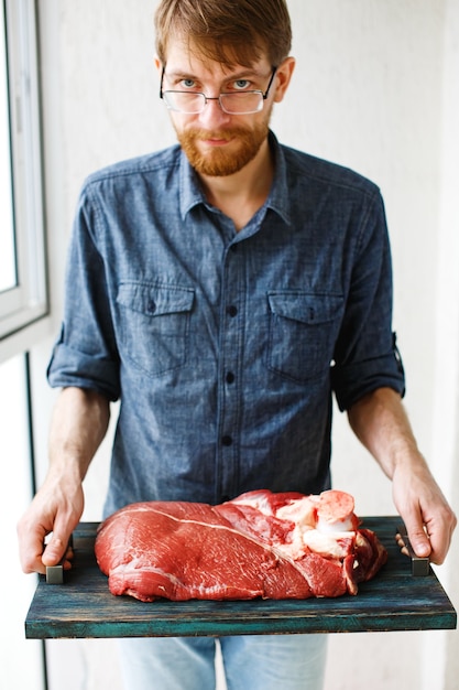 Hombre sujetando la bandeja con carne fresca de vacuno