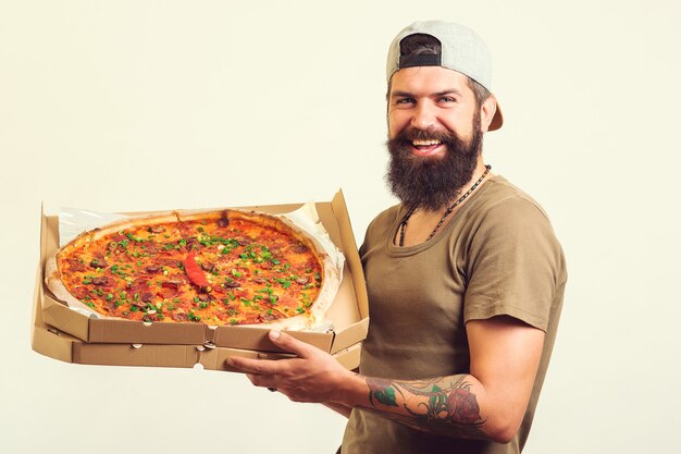 Hombre sujetando una bandeja para hornear con deliciosa pizza en las manos