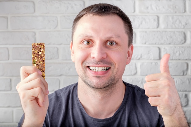 Foto hombre sujetando la barra de granola marrón