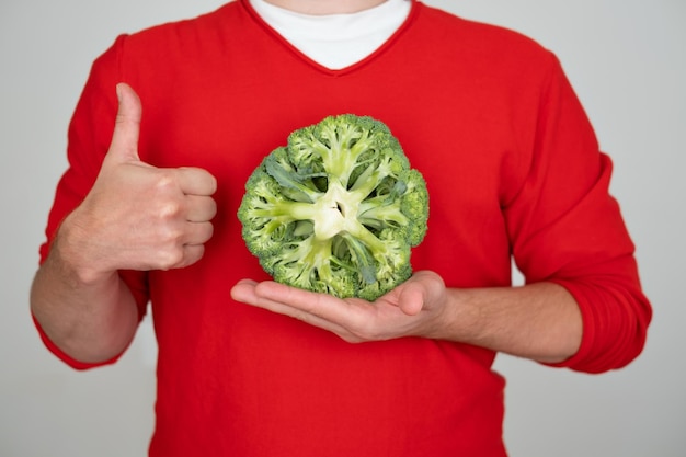 Hombre sujetando brócoli fresco verde aislado sobre fondo blanco.