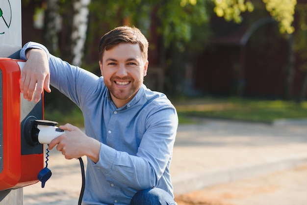 Hombre sujetando el cable de carga de energía para coche eléctrico