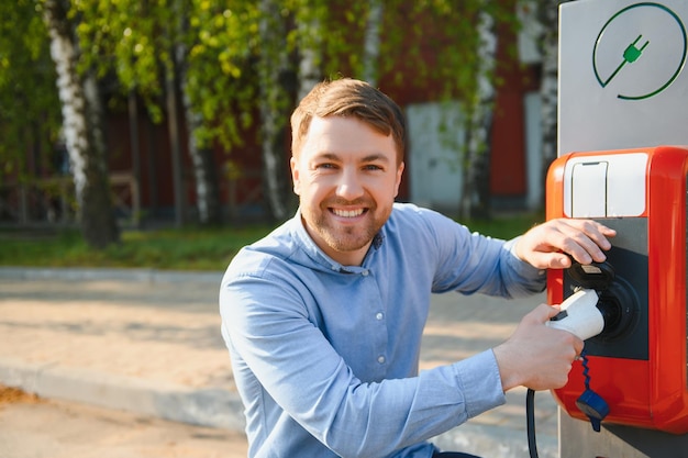 Hombre sujetando el cable de carga de energía para coche eléctrico
