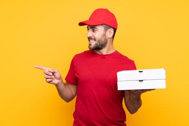 Hombre sujetando cajas de pizzas sobre pared aislada