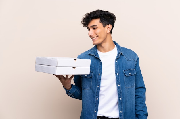 Hombre sujetando cajas de pizzas sobre pared aislada