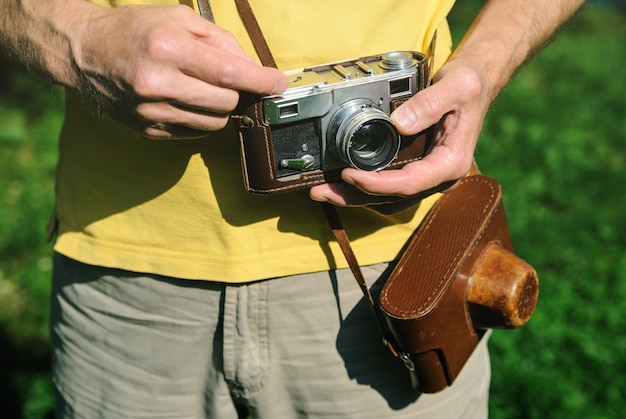 Hombre sujetando una cámara vintage ajustando la lente