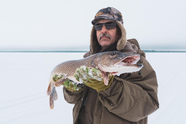 Hombre sujetando capturas de pesca de lucio de invierno