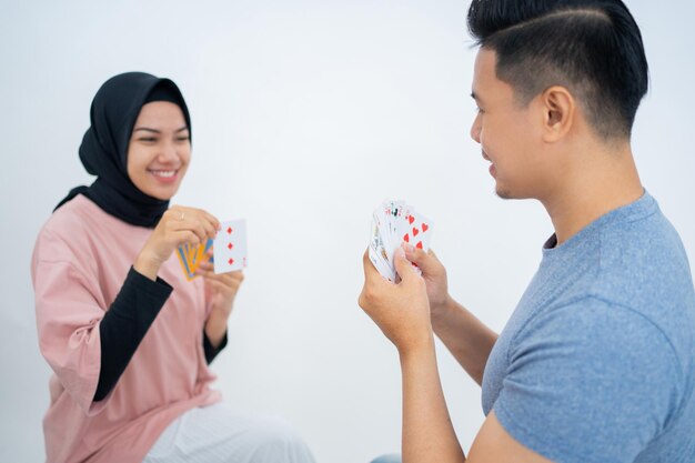 Hombre sujetando cartas mientras juega a las cartas con una amiga