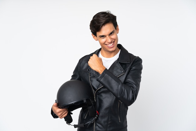 Hombre sujetando un casco de moto sobre pared blanca aislada celebrando una victoria