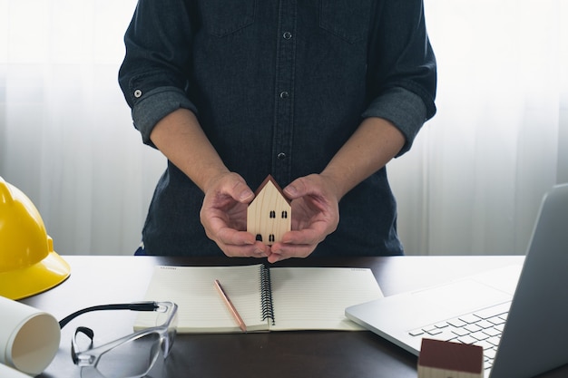 Foto hombre sujetando casita de madera en la oficina