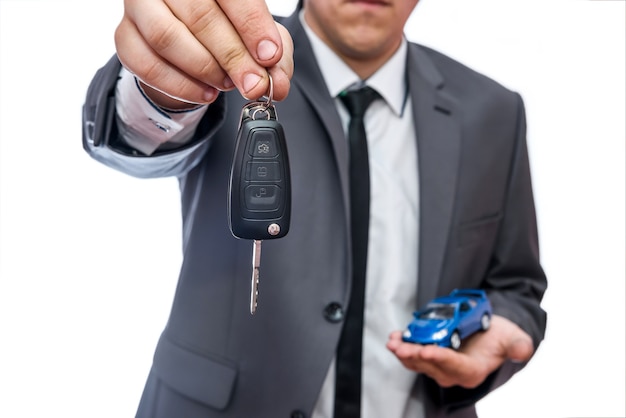 Hombre sujetando coche de juguete y llaves aislado en blanco