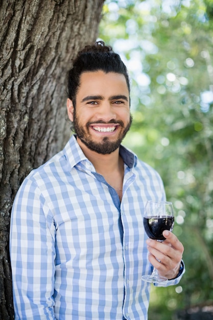 Hombre sujetando una copa de vino en el parque