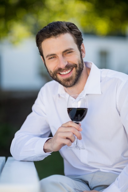 Hombre sujetando una copa de vino en el parque