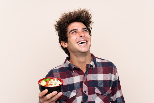 Foto hombre sujetando un cuenco lleno de fideos mirando hacia arriba mientras sonríe