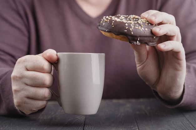 Hombre sujetando donas glaseadas y una taza de café