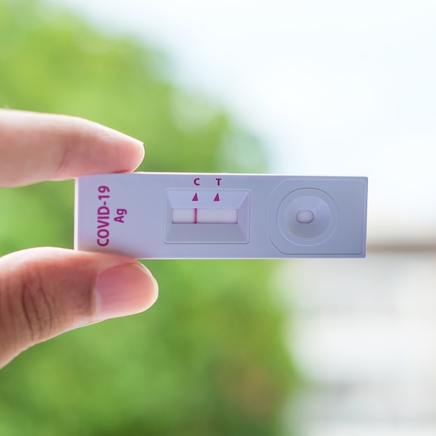 Hombre sujetando el kit de prueba rápida de antígenos con resultado negativo durante la prueba con hisopo COVID-19. Concepto de autoprueba nasal o casera de coronavirus, bloqueo y aislamiento del hogar