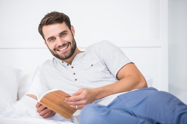 Hombre sujetando el libro en la cama en su casa